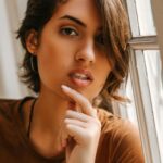 A thoughtful portrait of a woman with short hair by the window exuding confidence and allure.